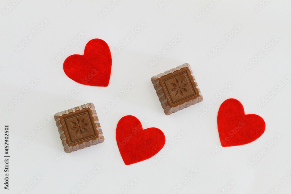 Milky chocolates and red hearts on white background
