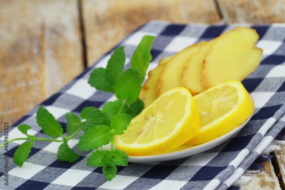 Slices of fresh lemon and fresh mint leaves on saucer