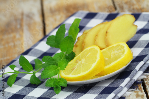 Obraz na płótnie Slices of fresh lemon and fresh mint leaves on saucer
w salonie
