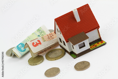 Obraz na płótnie Model house with British pound notes and coins on white background
w salonie