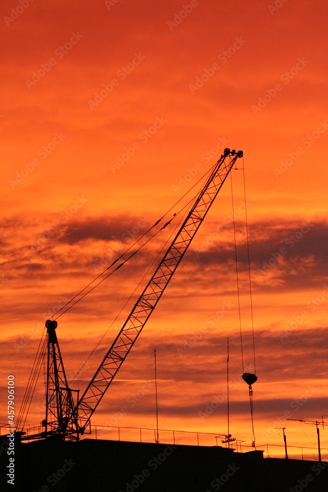 Sunset photography. A large construction crane is depicted against a bright orange background. The photograph conveys a mood of calm and relaxation.