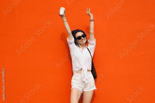 Image of cute young lady hands up and standing isolated over orange background. Looking camera.