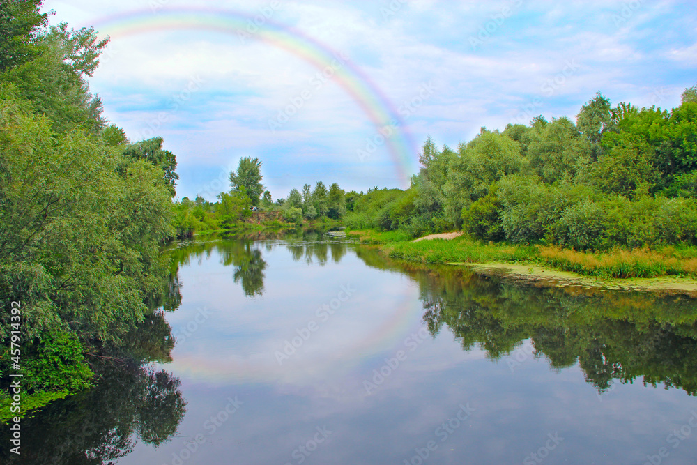Bright double rainbow in sky with clouds above river. Natural landscape Bright double rainbow in sky with clouds above river. Natural landscape