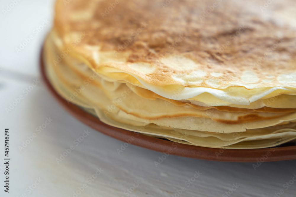 Crepes, thin pancakes on a plate on a white wooden table Crepes, thin pancakes on a plate on a white wooden table