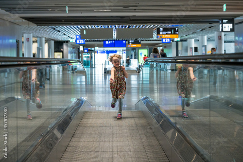 Cute blonde girl running on speed escalator at airport. photo