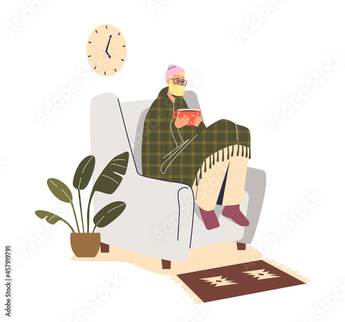 Freezing man sit in armchair at home under blanket wear hat indoors warming hands at hot cup