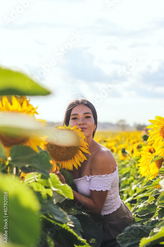 Beautiful brunette woman in a white top on the field with sunflowers. Yellow sunflowers. Close plan.