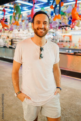 A man with a beard and a sunglasses in the white t-shirt and shorts at the fair