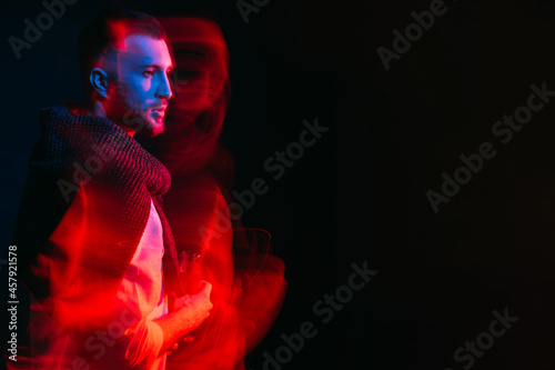 Thoughtful man. Party mood. Holiday spirit. Festive drink. Serious handsome guy holding glass of champagne long exposure red blue neon light motion blur on black copy space.