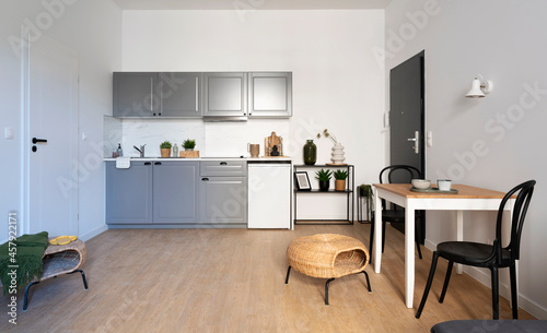 Modern kitchen interior with dinig room in small apartment with wooden floor and white wall. Stylish furniture in kitchen with table and chairs. © photosbysabkapl