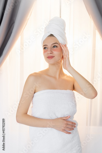 Spa procedure. Beautiful woman. Skin care treatment. Rejuvenation cosmetic. Home looking smiling lady with pink hydrogel under eye pads posing light room interior.