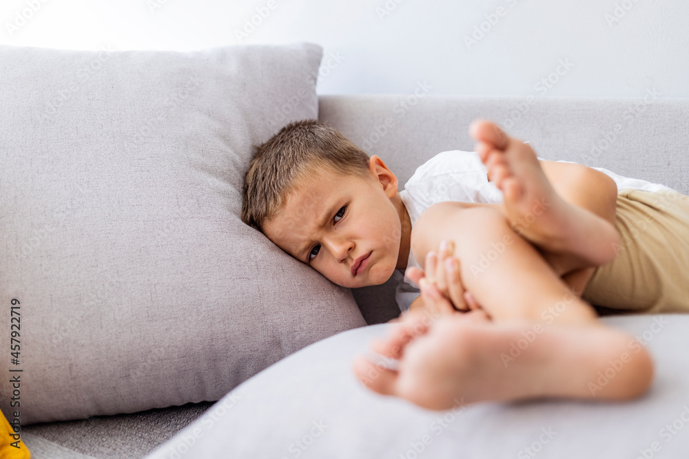 Cute angry boy. Morning home. Naughty little boy. Angry little boy frowned while sitting in bed and looking at camera. Angry boy with furrowed brows. Offended boy sitting on sofa