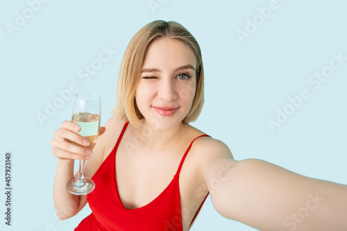 Party stream. Female blogger. Selfie photo. Festive celebration. Pretty winking woman glass of champagne make invisible video isolated blue. © golubovy