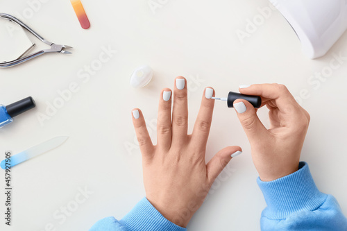 Woman doing manicure on white background