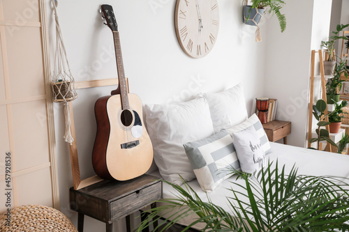 Interior of stylish bedroom with guitar