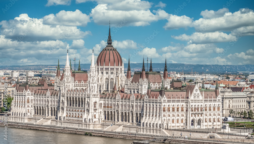 Obraz premium Summer view of the Hungarian Parliament built in Neo-Gothic style along the Danube river with perfect symmetry with cloudy blue sky