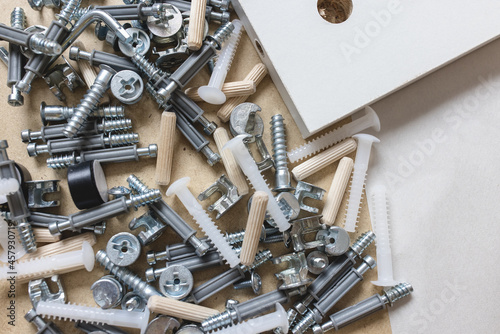 Opened box with furniture assembly parts and tools on the floor. Self assembling and DIY furniture at home concept. Bolts and screws closeup photo