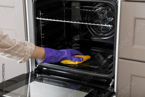 Woman cleaning oven in kitchen