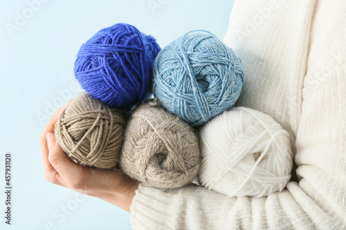 Woman holding knitting yarn on color background, closeup