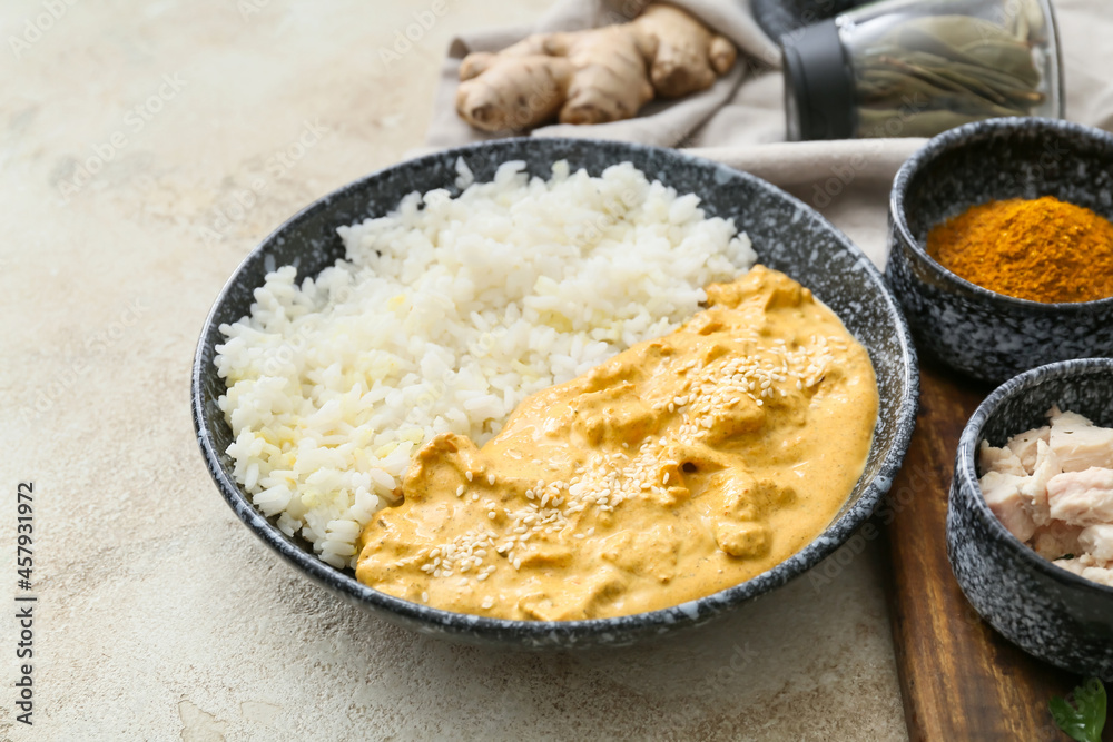Bowl of tasty chicken curry with rice and ingredients on light background Bowl of tasty chicken curry with rice and ingredients on light background