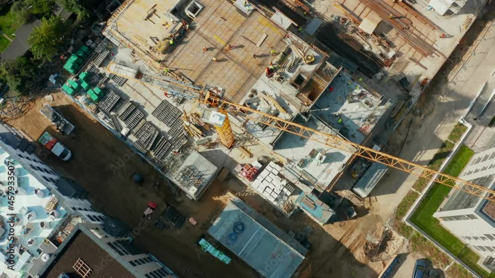 Aerial view of the construction of a residential building with tower cranes and workers working on the construction site, heavy machinery is working. Builders are building a house. Aerial view of the construction of a residential building with tower cranes and workers working on the construction site, heavy machinery is working. Builders are building a house.