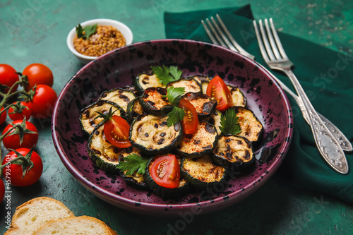 Plate with tasty grilled zucchini on color background