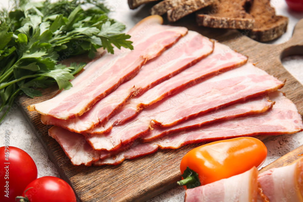 Wooden board with slices of tasty smoked bacon and fresh vegetables on light background Wooden board with slices of tasty smoked bacon and fresh vegetables on light background