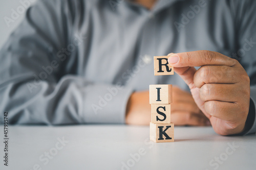 Hand hold wooden block with the word "RISK". Concept risk