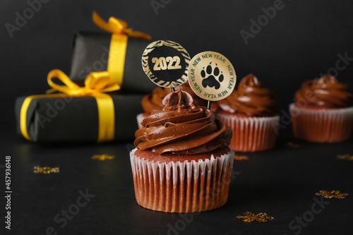 Tasty cupcake for New Year 2022 celebration on dark background