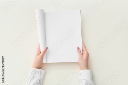 Female hands with blank magazine on light background © Pixel-Shot