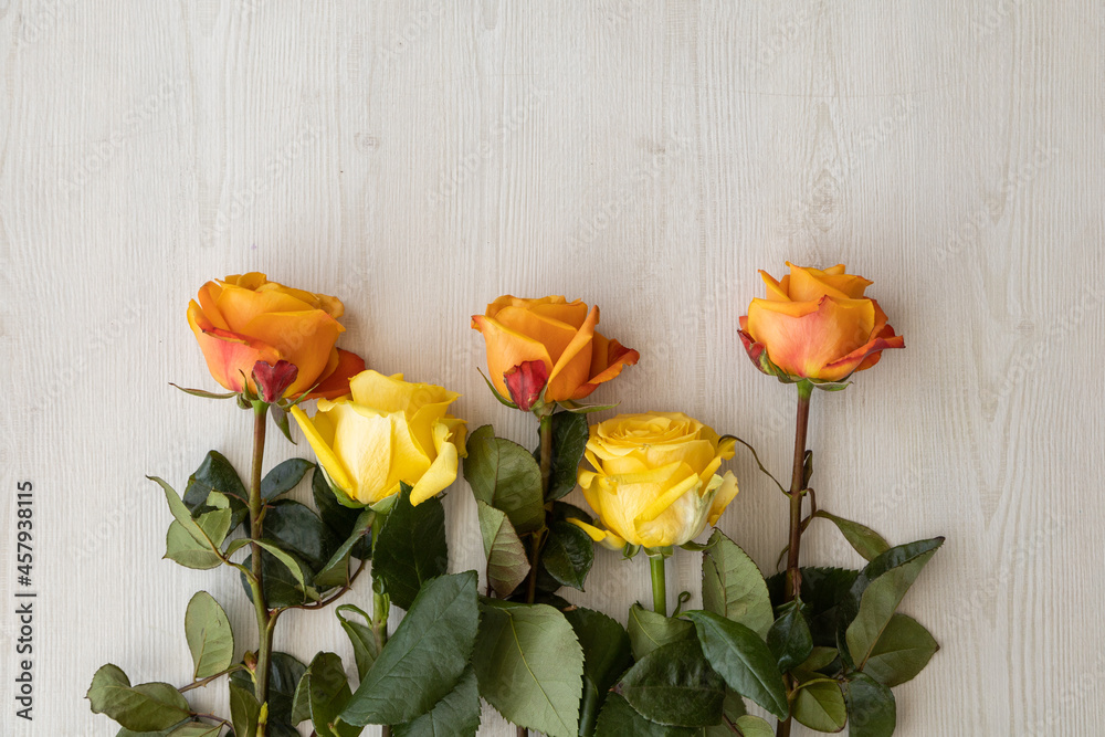 bouquet of yellow roses with orange edge lying neatly on a wooden table, detail of the petals, stem and leaves, nature in studio, backgrounds with natural flowers bouquet of yellow roses with orange edge lying neatly on a wooden table, detail of the petals, stem and leaves, nature in studio, backgrounds with natural flowers