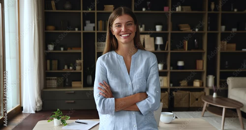Portrait of smiling confident young female successful freelancer self employed entrepreneur standing at home office with arms crossed on chest. Happy teen lady student remote employee look at camera
