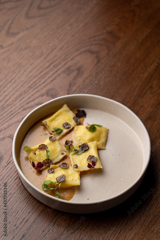 Portion of ricotta ravioli with truffle sauce, top view with a bottle of white wine Portion of ricotta ravioli with truffle sauce, top view with a bottle of white wine
