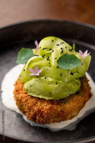 Crab croquette roasted and breaded with avocado puree, close up, commercial photo