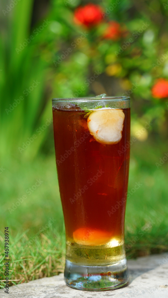 Ice tea with lychee fruit in glass. Green background Ice tea with lychee fruit in glass. Green background