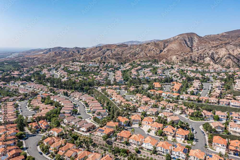 Aerial view of modern homes surrounded by hills on a clear day.