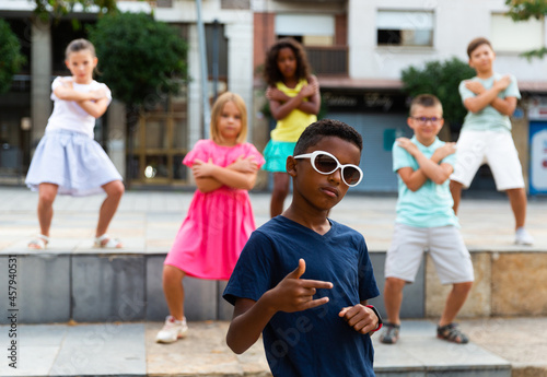 Group of multiracial positive kids performing street dance outdoors.