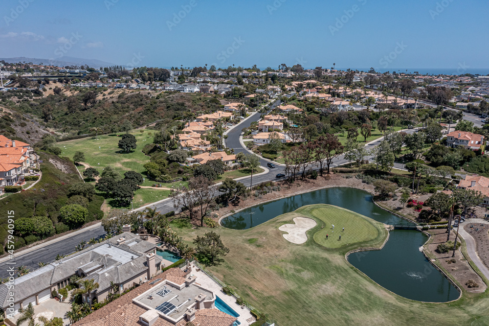 Aerial view of a putting green surrounded by water in an upscale neighborhood.