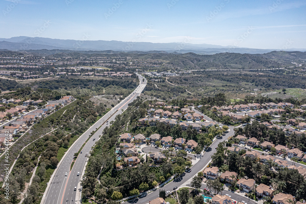 Aerial view of a highway winding through an upscale suburban neighborhood, surrounded by hills