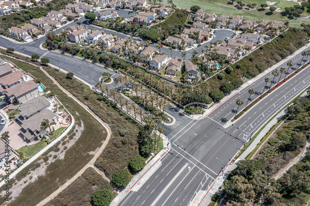 Gated entry to an upscale California neighborhood, aerial view of street lined with palm trees.