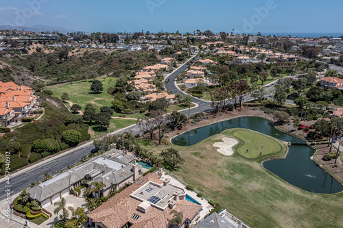 Aerial view of a putting green surrounded by water in an upscale neighborhood.