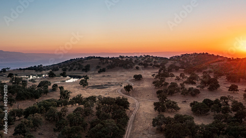 Aerial View of a Valley, Lake and Rolling Hills Covered in Oak Trees and Blanketed in a California Sunset photo