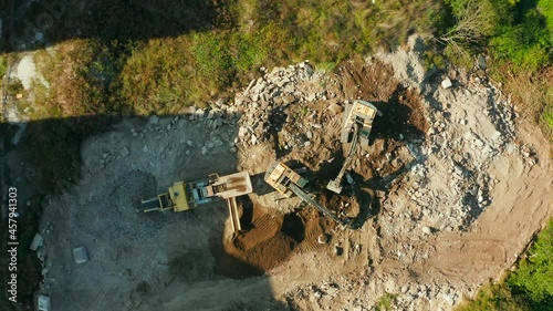 Top down aerial view of two Excavators loading rocks into a portable rock crusher. Equipment for the mining industry. A small crusher works with crushed rock.
