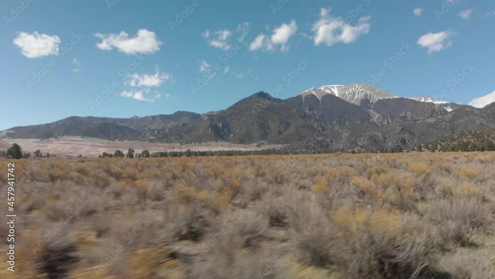 Aerial: Low dry shrub desert flight with snow-capped mountain beyond Aerial: Low dry shrub desert flight with snow-capped mountain beyond