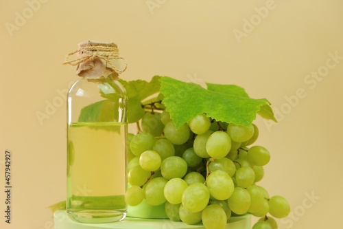 Grape seed oil.bottle and bunch of green grapes on green podium on a beige background. Organic Natural Bio Grape Seed Oil. 