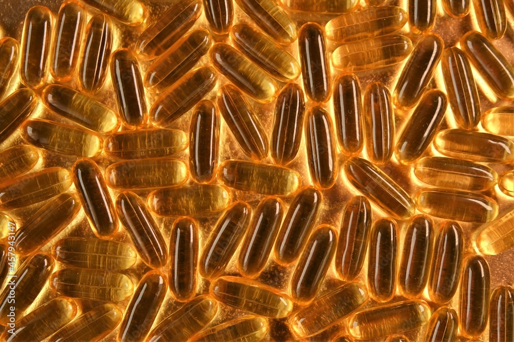 Fish oil on a gold background .omega fatty acids.Natural supplements.Healthy eating and food supplements.Natural supplements . High quality photo Fish oil on a gold background .omega fatty acids.Natural supplements.Healthy eating and food supplements.Natural supplements . High quality photo