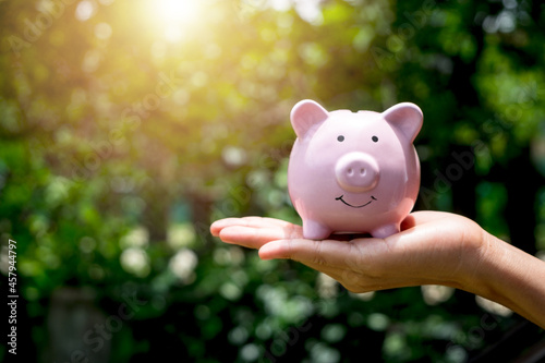 Woman hand holding piggy bank with sunrise, saving, charity, fundrasing community care, superannuation, financial crisis concept