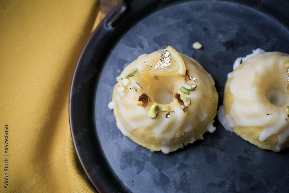 Lemon cake with sugar sweet icing on yellow and black background. Cake with citrus, poppy, traditional american cuisine in dark tone Lemon cake with sugar sweet icing on yellow and black background. Cake with citrus, poppy, traditional american cuisine in dark tone