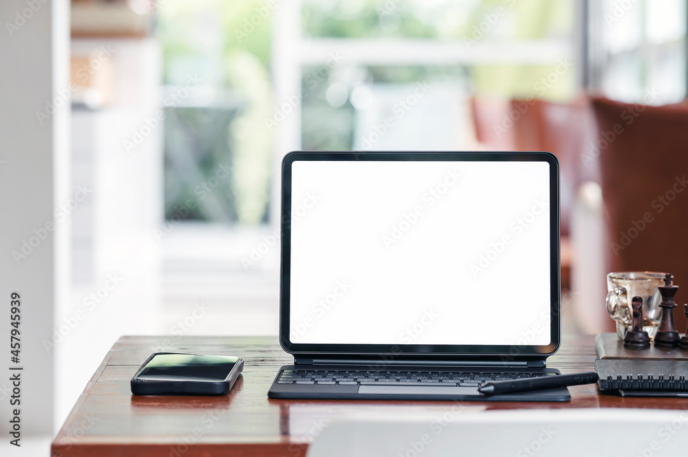 White screen tablet with magic keyboard and smartphone on the table in living room. White screen tablet with magic keyboard and smartphone on the table in living room.
