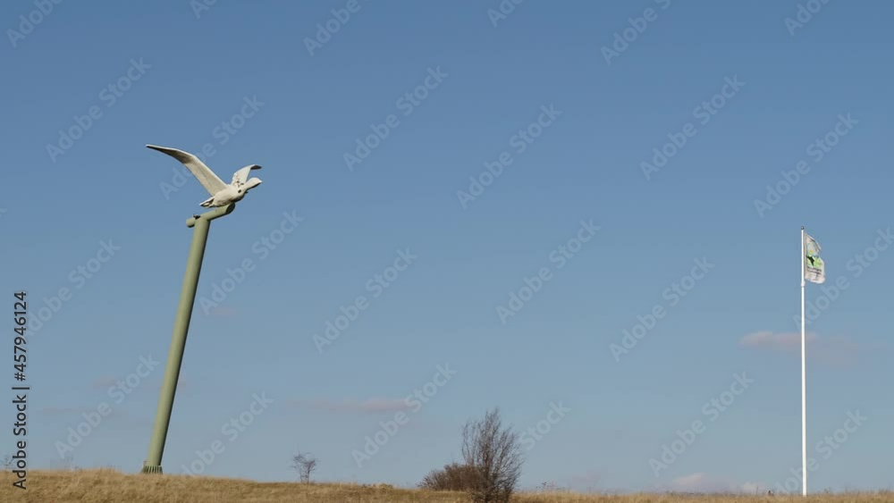 a statue of a bird on a high pillar with a flag blowing in the wind - calm slow shot a statue of a bird on a high pillar with a flag blowing in the wind - calm slow shot